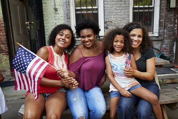 Portrait of smiling women and girl posing with American flag