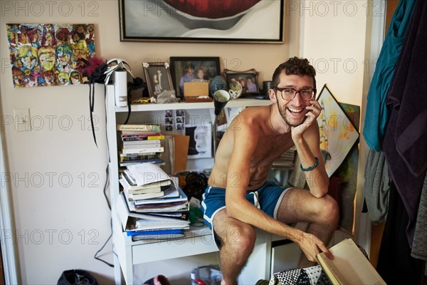 Caucasian man sitting on messy desk reading book