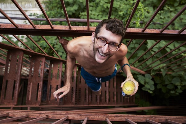 Caucasian man standing on urban fire escape drinking orange juice