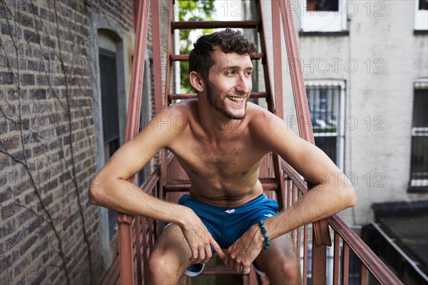 Caucasian man sitting on urban fire escape