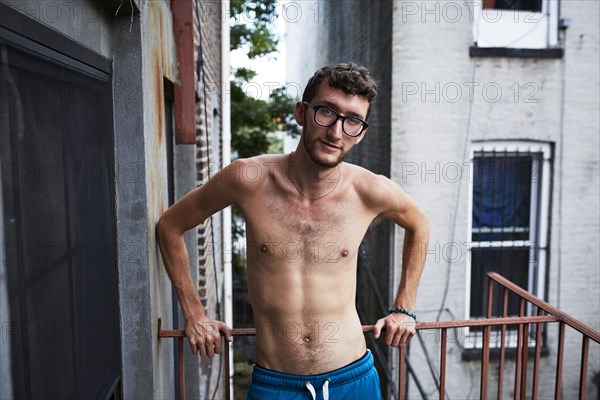 Caucasian man standing on urban fire escape