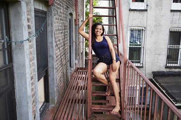 Portrait of smiling woman sitting on urban fire escape