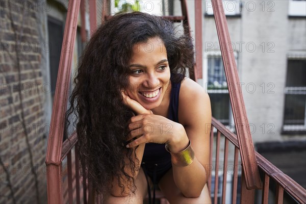 Portrait of smiling woman relaxing on urban fire escape