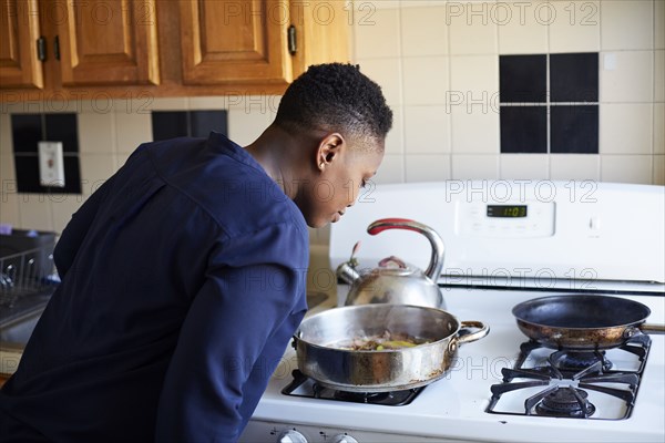 Black woman smelling food cooking in pan on stove