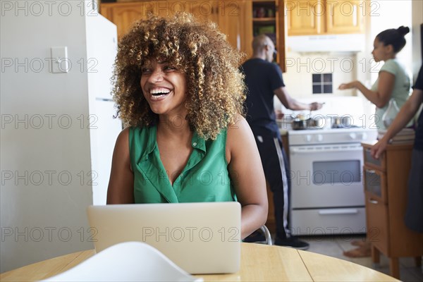 Laughing Black woman using laptop at table