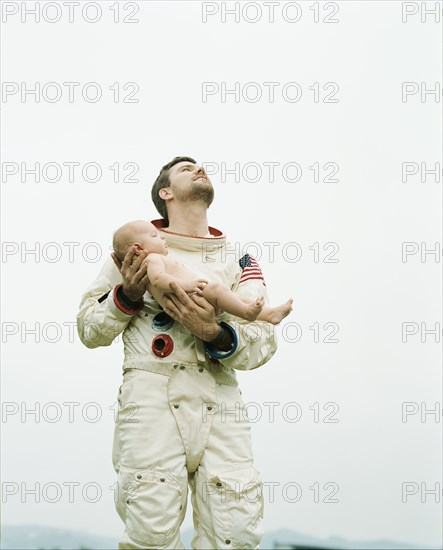 Astronaut holding baby outdoors