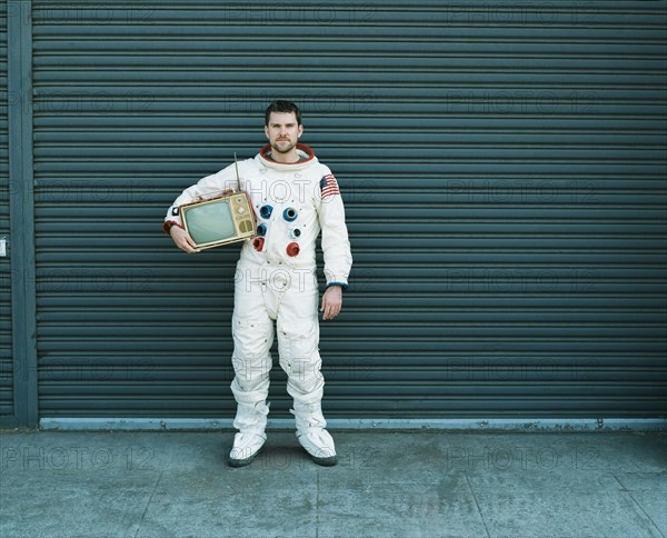 Astronaut carrying television on city street