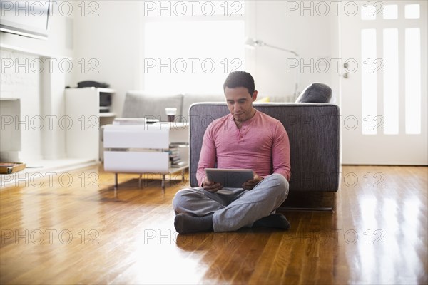 Mixed race man using digital tablet in living room