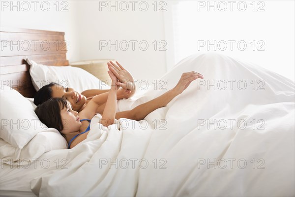 Mother and daughter laying in bed