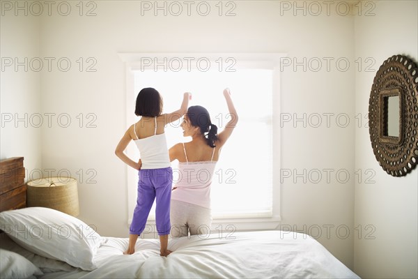 Mother and daughter playing on bed