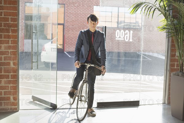 Korean businessman wheeling bicycle in office