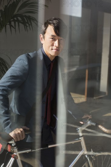 Korean businessman wheeling bicycle in office