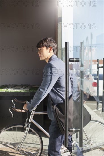 Korean businessman wheeling bicycle in office
