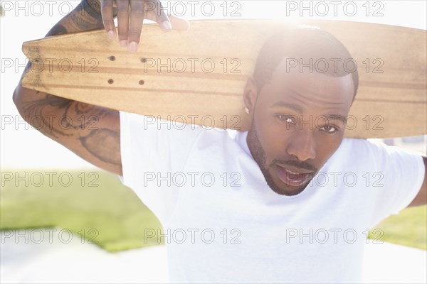 African American man carrying skateboard outdoors