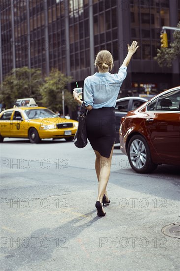 Caucasian woman hailing taxi in urban street