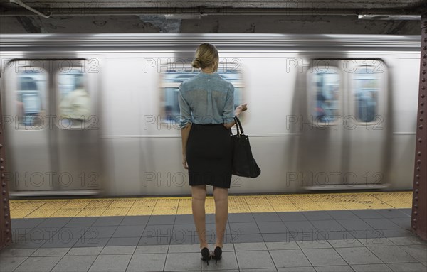 Caucasian woman standing near passing subway in train station