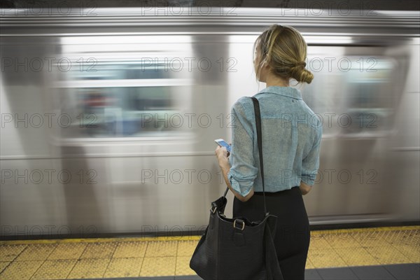 Caucasian woman standing near passing subway in train station