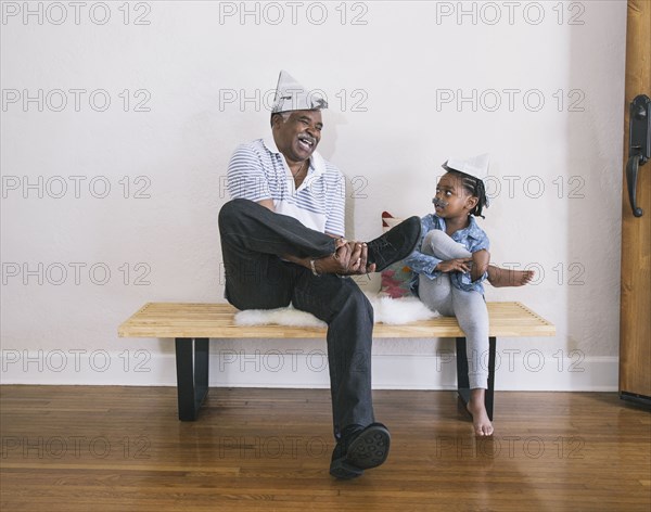 African American grandfather and granddaughter playing on bench