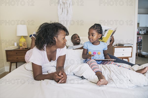 African American parents and daughter on bed