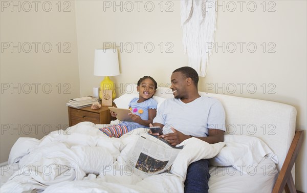African American father and daughter sitting on bed