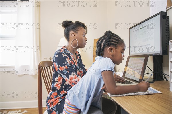 African American mother with daughter working from home