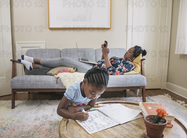 African American mother and daughter relaxing in living room