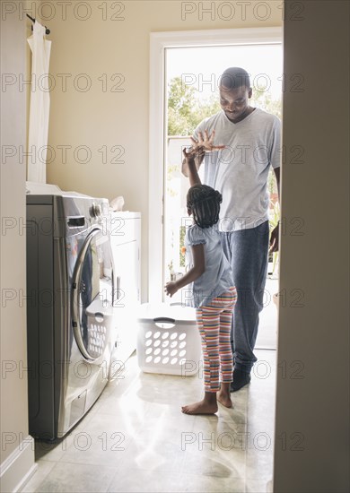 African American father and daughter doing laundry