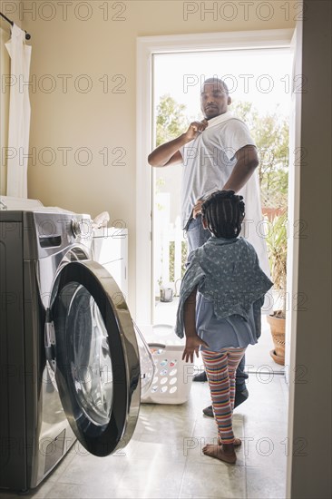 African American father and daughter doing laundry