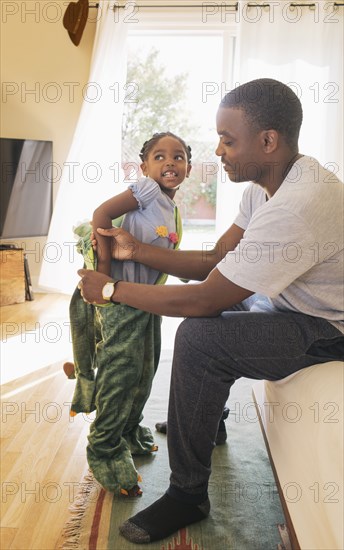 African American father helping daughter put on costume