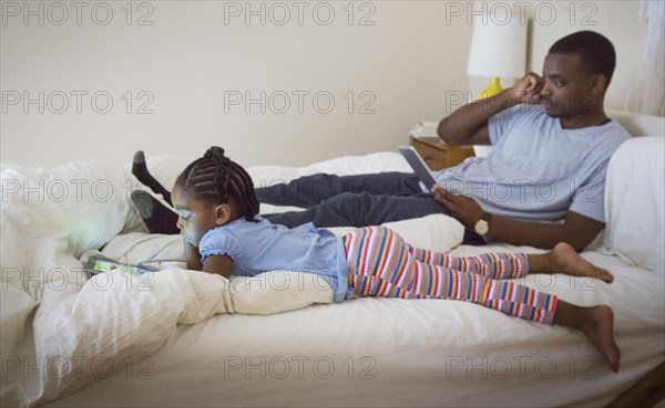 African American father and daughter relaxing on bed