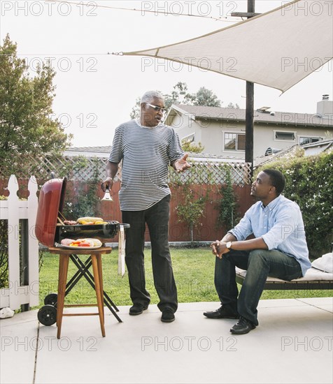 African American father and son talking at barbecue