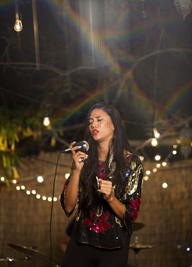 Mixed Race woman holding microphone and singing