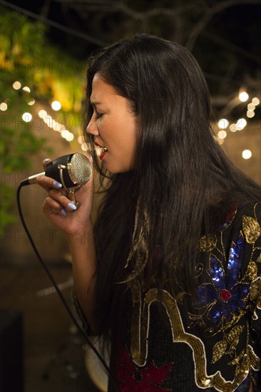 Mixed Race woman holding microphone and singing