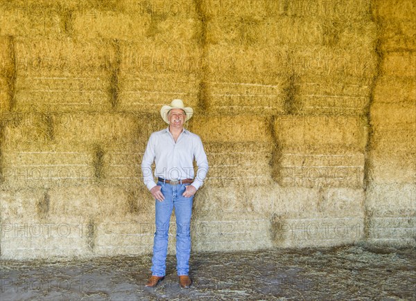 Caucasian farmer standing with hay bales