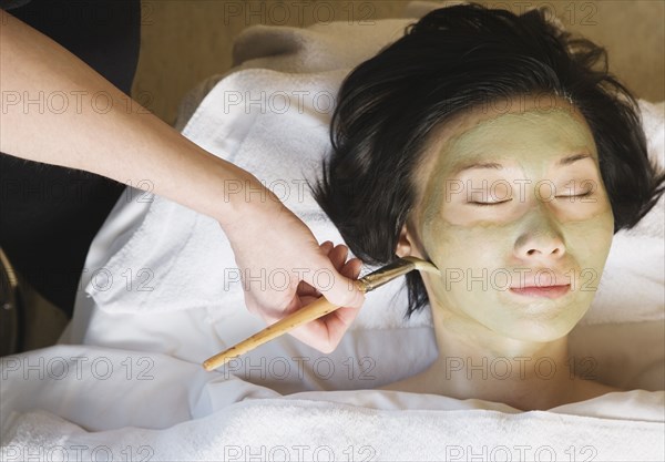 Asian woman receiving spa facial treatment