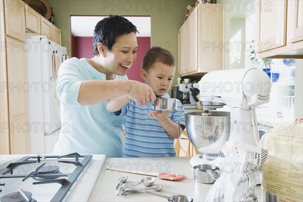 Asian mother and young son baking in kitchen