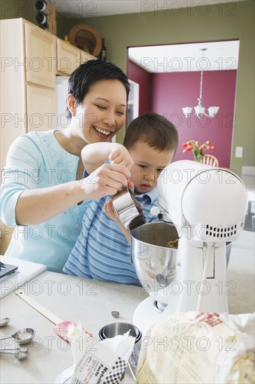 Asian mother and young son baking in kitchen