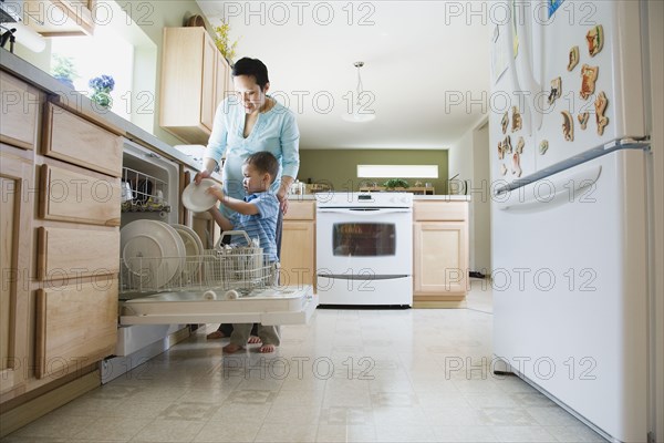 Mother and young son putting dishes in dishwasher