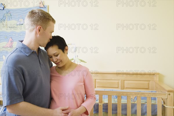 Pregnant couple hugging in nursery