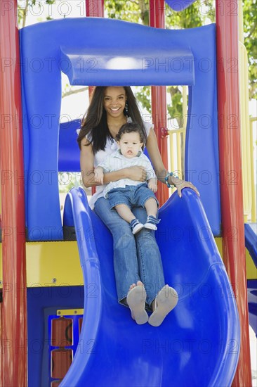 Young African mother on slide with baby on lap