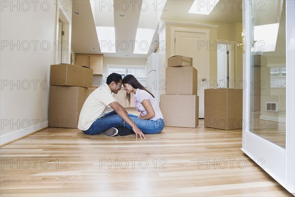 Asian couple smiling at each other in new house