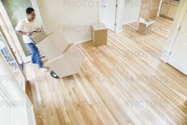 Asian man moving boxes in new house