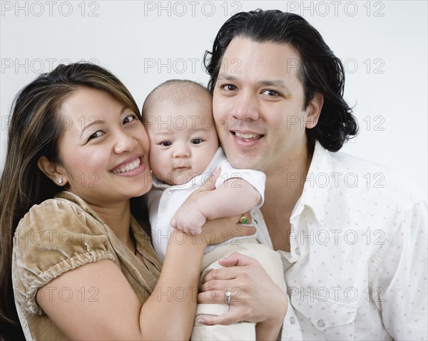 Asian parents hugging baby