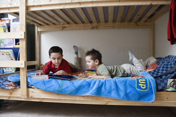 Hispanic brothers reading in bed