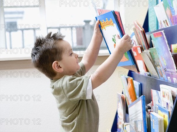 Hispanic boy taking book from rack