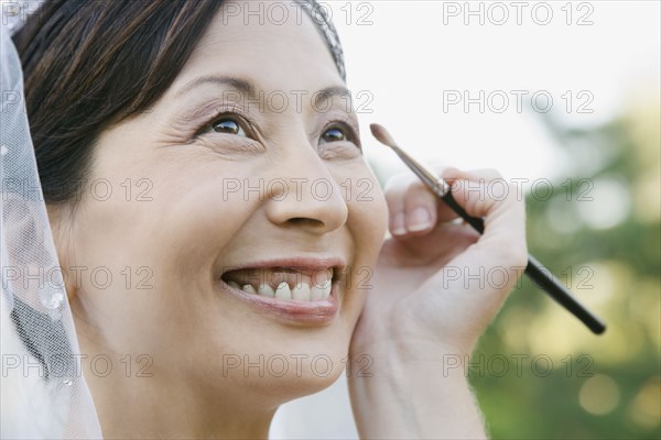 Asian bride having makeup applied