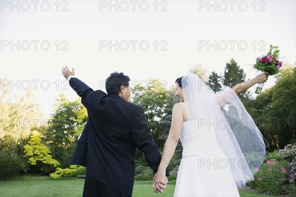 Asian newlyweds with arms raised