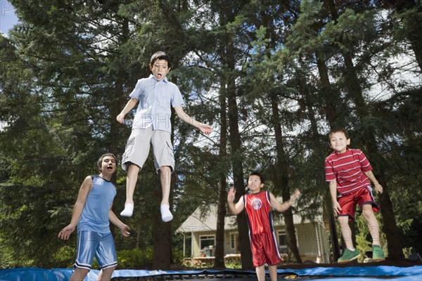 Asian brothers jumping on trampoline