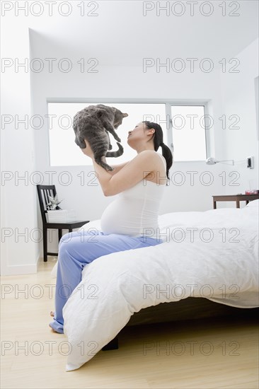 Pregnant Asian woman holding cat