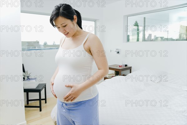 Pregnant Asian woman holding stomach